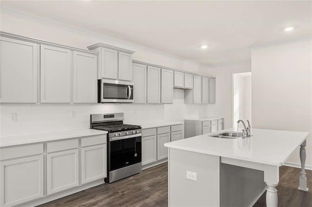 kitchen with a sink, light countertops, appliances with stainless steel finishes, dark wood-style floors, and a center island with sink