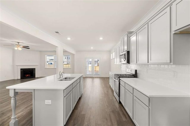 kitchen featuring a center island with sink, open floor plan, light countertops, stainless steel appliances, and a sink