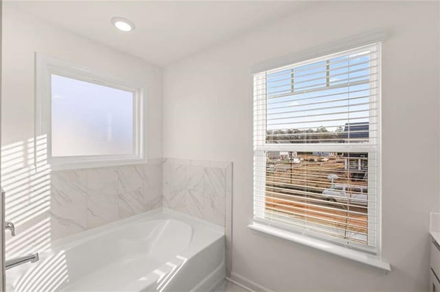 bathroom with recessed lighting, vanity, and a bath