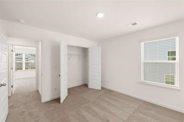 unfurnished bedroom with a closet, light carpet, visible vents, and baseboards