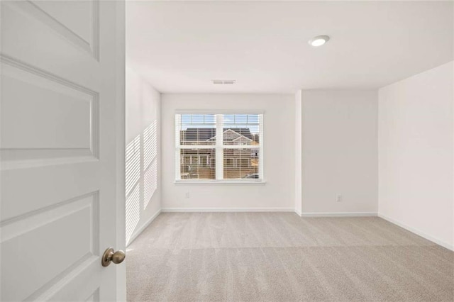 spare room with light carpet, visible vents, and baseboards