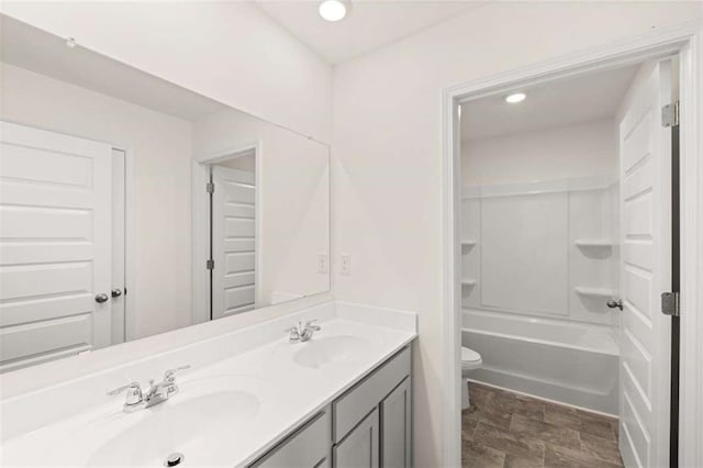 bathroom featuring double vanity, a sink, toilet, and recessed lighting