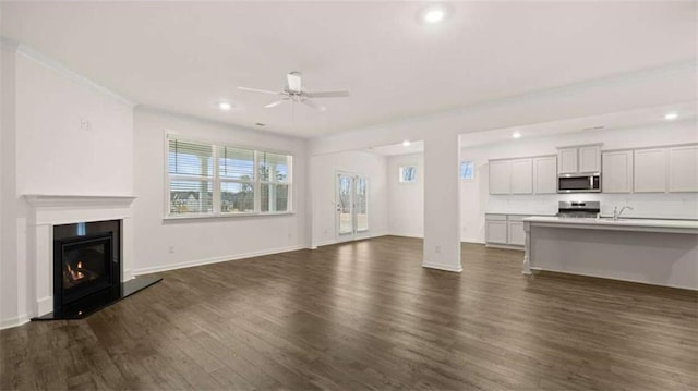 unfurnished living room featuring ceiling fan, recessed lighting, dark wood finished floors, baseboards, and a glass covered fireplace