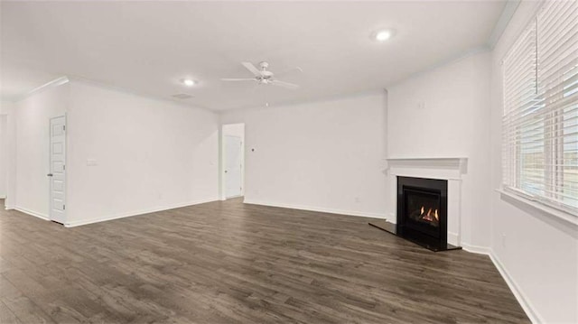 unfurnished living room featuring a warm lit fireplace, baseboards, dark wood finished floors, ceiling fan, and recessed lighting