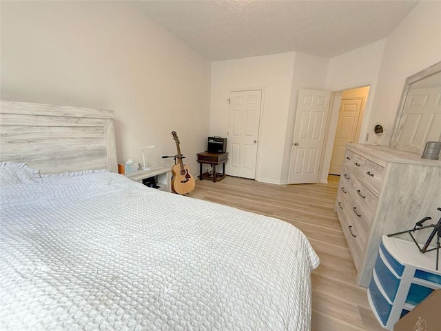 260 Ruby Forest Pkwy, Suwanee, GA 30024 - bedroom featuring light wood-style floors, a textured ceiling, lofted ceiling, and baseboards