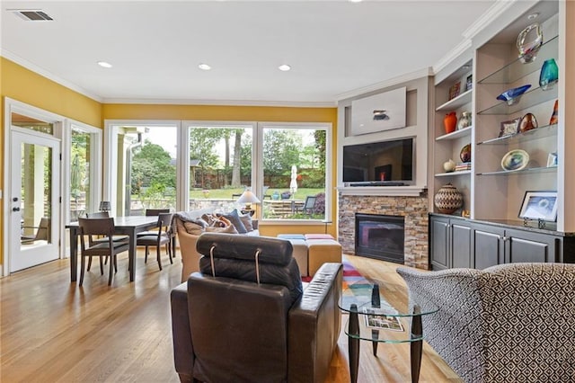 living area featuring a stone fireplace, visible vents, crown molding, light wood finished floors, and recessed lighting