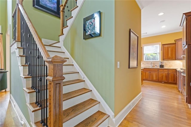 stairway featuring baseboards, ornamental molding, recessed lighting, and wood finished floors