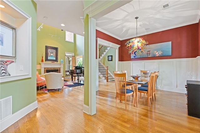 dining space with stairway, a fireplace, wood finished floors, and visible vents