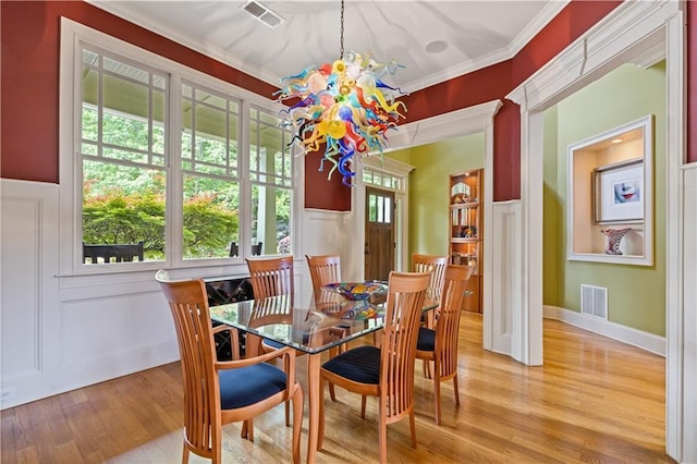 dining room with a chandelier, visible vents, ornamental molding, and wood finished floors
