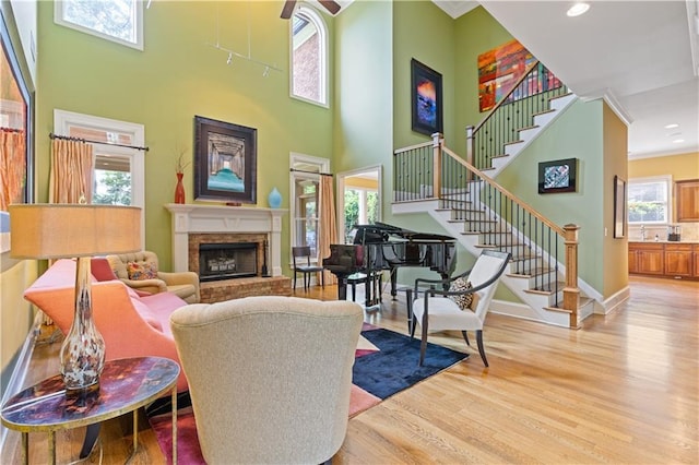 living area with a towering ceiling, wood finished floors, stairway, baseboards, and a fireplace with raised hearth