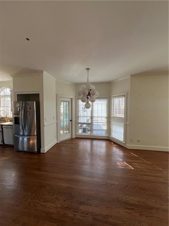 unfurnished living room featuring a healthy amount of sunlight, dark wood-type flooring, and an inviting chandelier