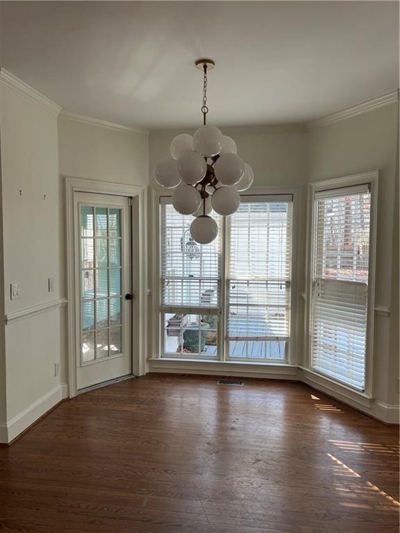 unfurnished dining area featuring dark wood-type flooring, a wealth of natural light, and a notable chandelier