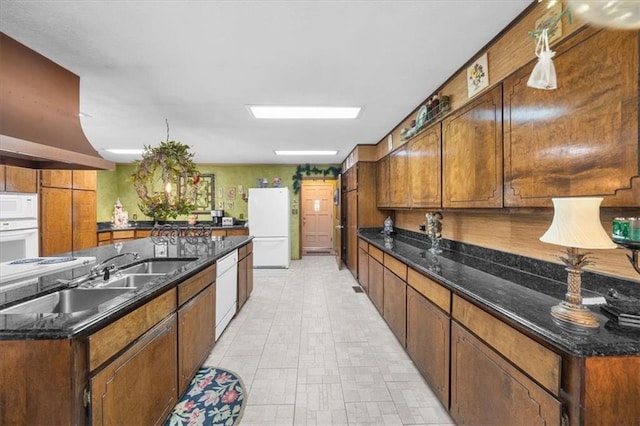 kitchen featuring ventilation hood, dark stone countertops, and white appliances