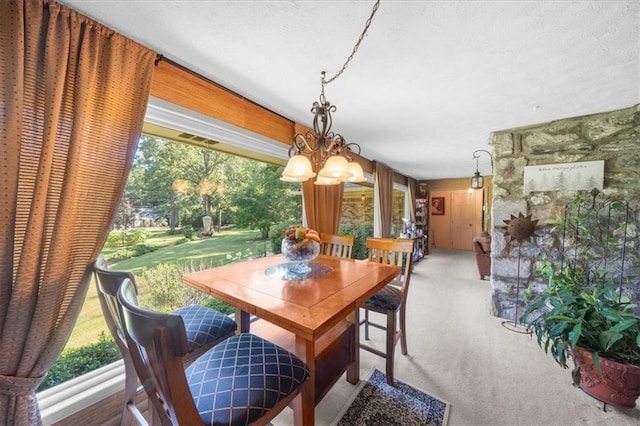 dining area featuring an inviting chandelier, carpet flooring, and a textured ceiling