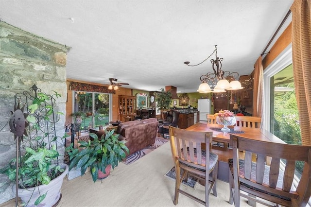 dining room featuring ceiling fan with notable chandelier and light carpet