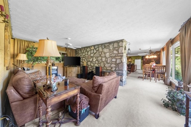 carpeted living room with a textured ceiling, ceiling fan with notable chandelier, wood walls, and a fireplace