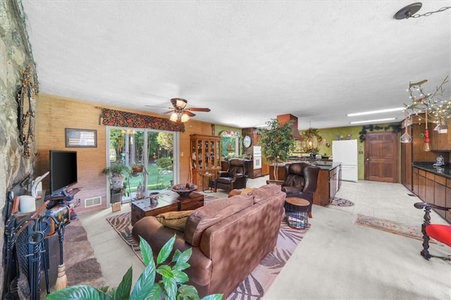 living room with ceiling fan, light colored carpet, and a textured ceiling