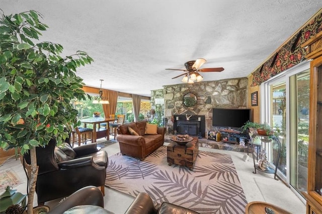 living room featuring ceiling fan with notable chandelier, a wood stove, and a textured ceiling