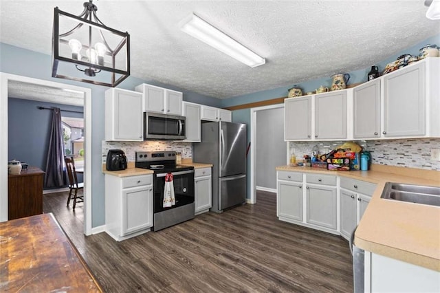 220 Brookstone Trl, Braselton, GA 30517 - kitchen with appliances with stainless steel finishes, dark wood-style flooring, decorative backsplash, light countertops, and a textured ceiling