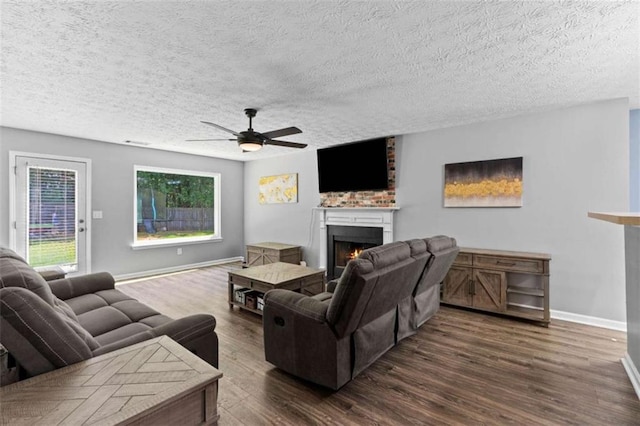 220 Brookstone Trl, Braselton, GA 30517 - living room with a lit fireplace, a ceiling fan, dark wood-type flooring, and a textured ceiling