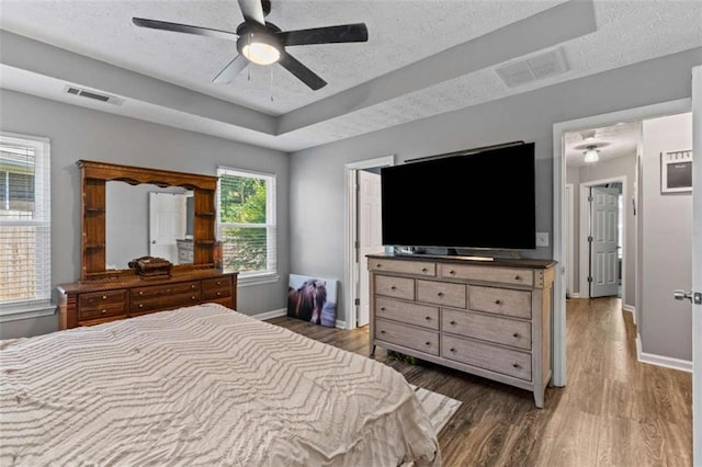 220 Brookstone Trl, Braselton, GA 30517 - bedroom featuring a textured ceiling, wood finished floors, multiple windows, a ceiling fan, and a raised ceiling