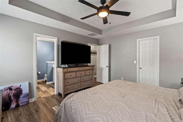 220 Brookstone Trl, Braselton, GA 30517 - bedroom with wood finished floors, a tray ceiling, a textured ceiling, ensuite bathroom, and a ceiling fan