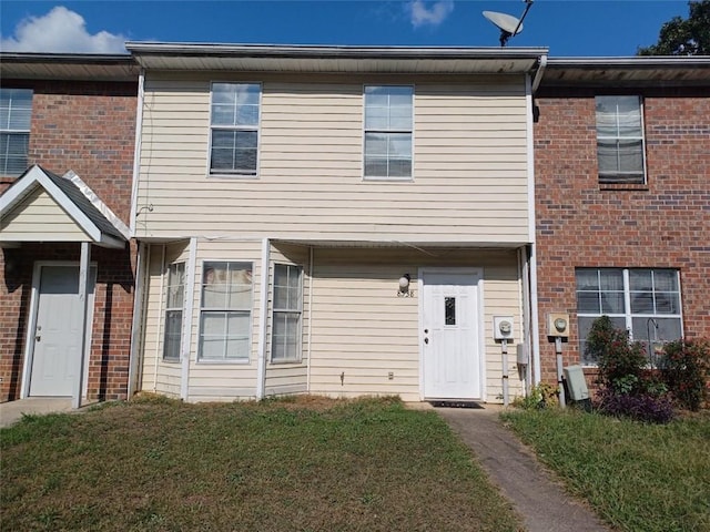 townhome / multi-family property featuring a front yard and brick siding