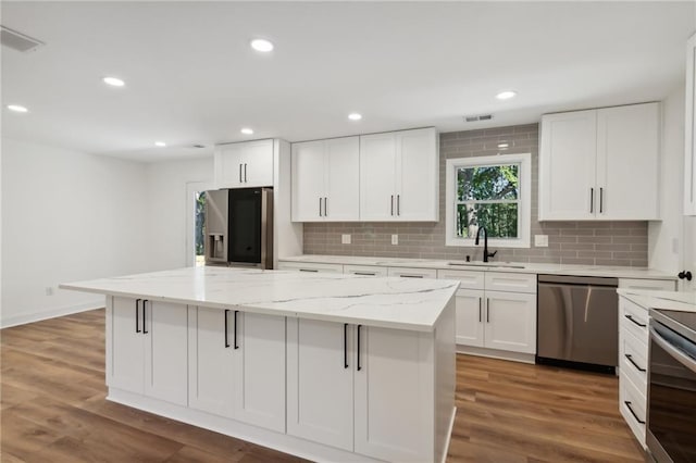 kitchen with sink, white cabinets, stainless steel appliances, and a kitchen island