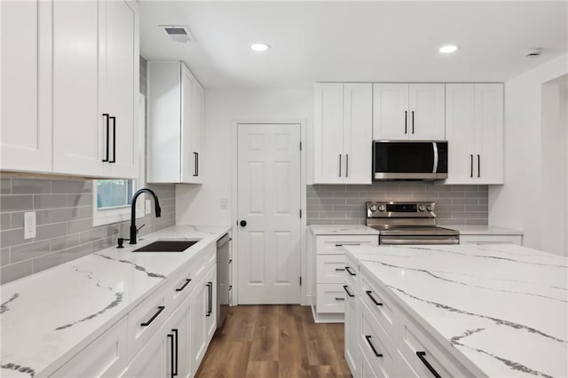 kitchen featuring hardwood / wood-style floors, white cabinetry, sink, and stainless steel appliances