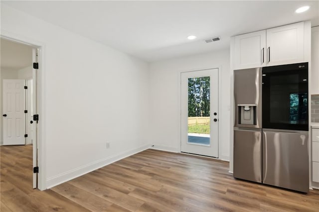 kitchen featuring white cabinets, stainless steel fridge with ice dispenser, and light hardwood / wood-style flooring