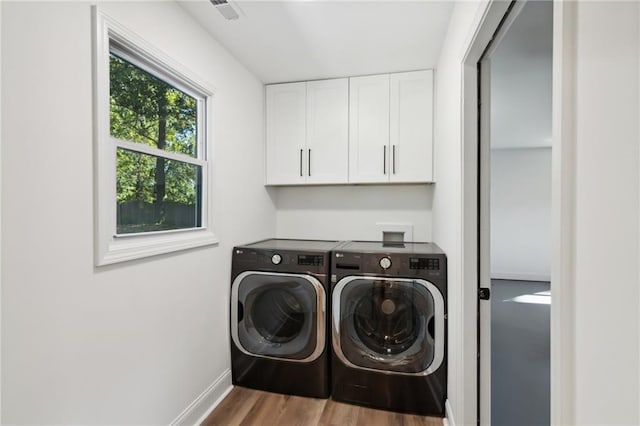 laundry room featuring hardwood / wood-style floors, cabinets, and washing machine and clothes dryer