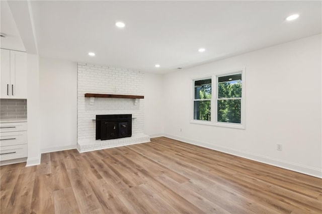 unfurnished living room with light hardwood / wood-style floors and a brick fireplace