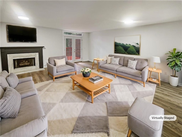 living area featuring french doors, baseboards, wood finished floors, and a fireplace