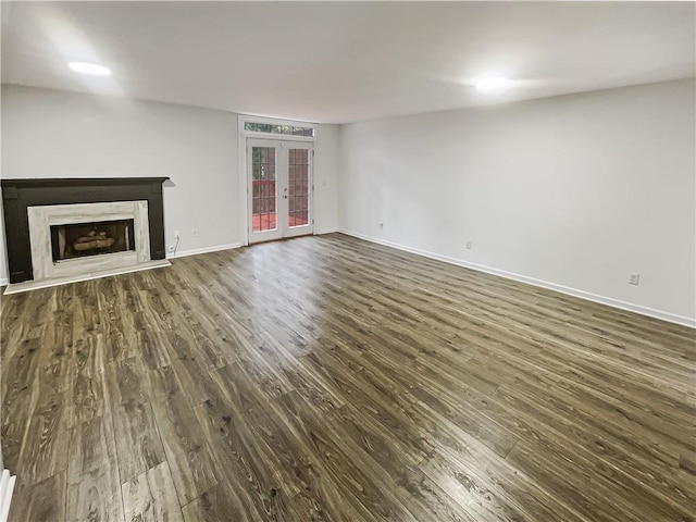 unfurnished living room with dark wood finished floors, french doors, baseboards, and a premium fireplace