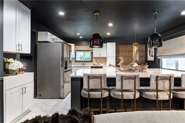 kitchen with a breakfast bar, marble finish floor, white cabinets, a kitchen island, and stainless steel fridge with ice dispenser