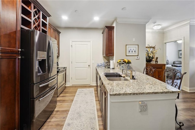 kitchen with sink, light stone counters, crown molding, appliances with stainless steel finishes, and light wood-type flooring