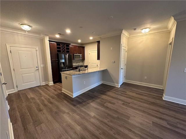 kitchen with light stone countertops, appliances with stainless steel finishes, kitchen peninsula, decorative backsplash, and sink