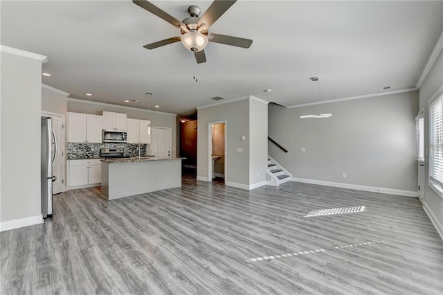 4421 Fulson Dr, Lilburn, GA 30047 - unfurnished living room featuring crown molding, ceiling fan, baseboards, stairway, and light wood-style floors