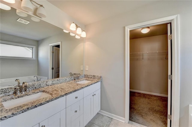4421 Fulson Dr, Lilburn, GA 30047 - full bathroom with double vanity, a walk in closet, baseboards, and a tub