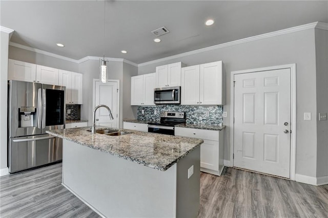 4421 Fulson Dr, Lilburn, GA 30047 - kitchen featuring appliances with stainless steel finishes, a sink, an island with sink, light wood finished floors, and backsplash