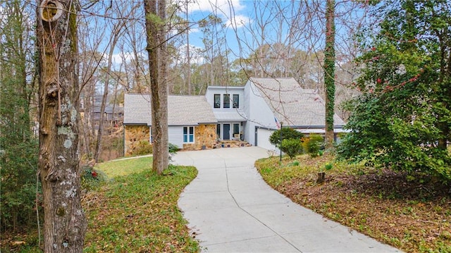 mid-century home featuring a garage, stone siding, and concrete driveway