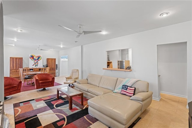 living area with light tile patterned flooring, ceiling fan, and baseboards
