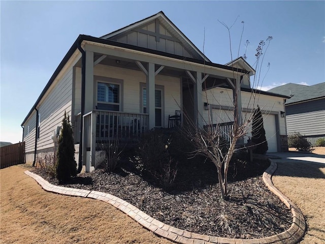 view of front of home with a porch, an attached garage, driveway, and board and batten siding