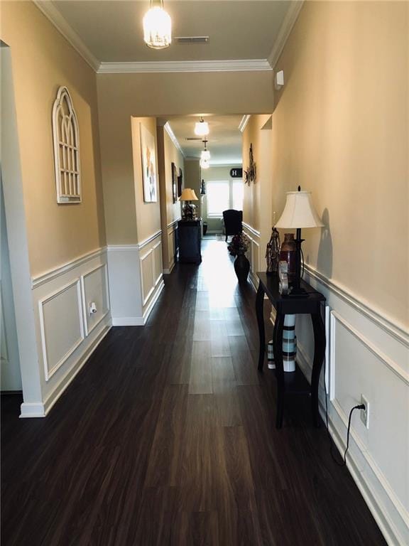 hall with dark wood finished floors, crown molding, visible vents, and wainscoting