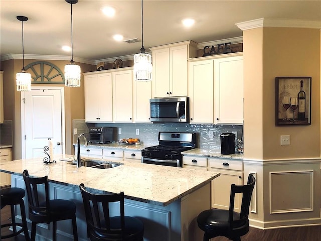 kitchen with visible vents, ornamental molding, a sink, appliances with stainless steel finishes, and a kitchen bar