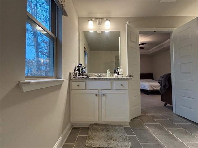 ensuite bathroom with ensuite bath, ceiling fan, vanity, and baseboards