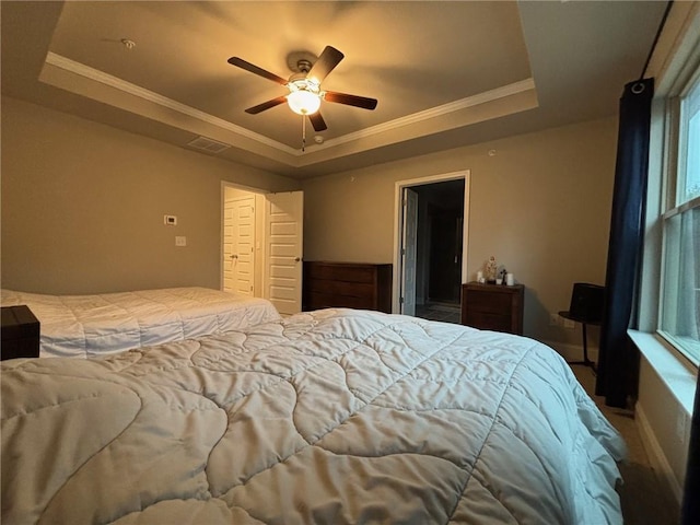 bedroom featuring ceiling fan, a tray ceiling, visible vents, and ornamental molding