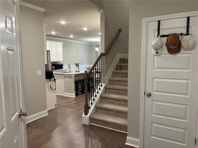 stairway featuring recessed lighting, crown molding, baseboards, and wood finished floors