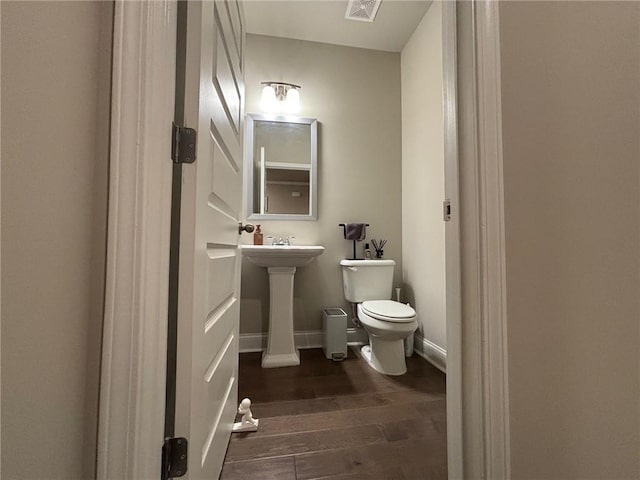 bathroom featuring visible vents, toilet, a sink, wood finished floors, and baseboards