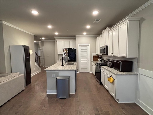 kitchen with stainless steel microwave, black microwave, dark wood finished floors, range with gas stovetop, and fridge